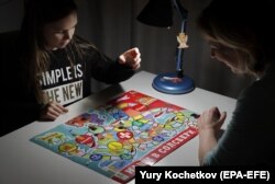 Дівчинка грає з матір’ю в настільну гру «Наші в Солсбері», Москва, січень 2019 року