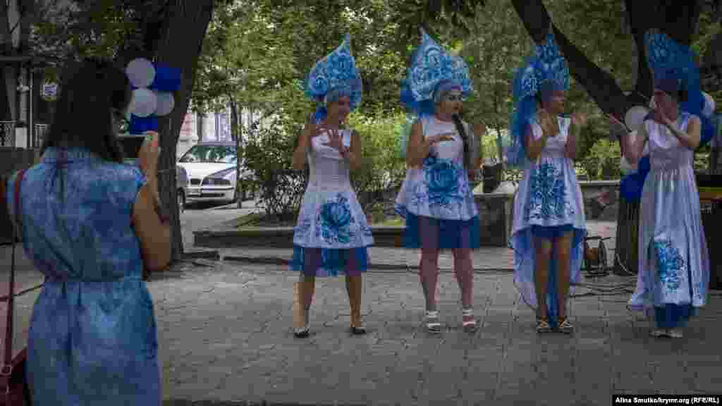 Участницы ярмарки танцуют возле стенда 