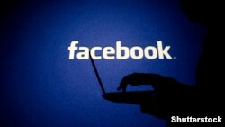 Georgia -- A woman works on his computer in front of Facebook sign