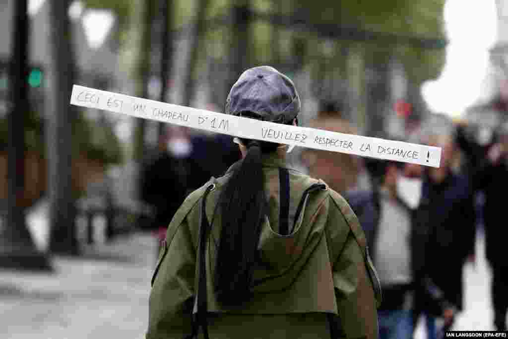 Жінка в кепці з причепленим написом «Це шапка діаметром 1 м. Будь ласка, дотримуйтесь дистанції», йде проспектом Єлисейські поля в Парижі 11 травня 2020 року в час, коли Франція розпочала поступове послаблення карантинних заходів через пандемію COVID-19