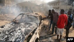 Men look at the wreckage of a car following a bomb blast at a church outside the Nigerian capital, Abuja, on December 25.