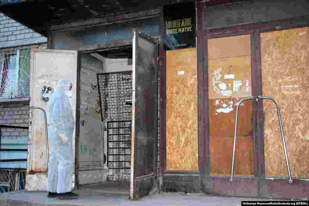 Медик у захисному костюмі перед одним із входів у гуртожиток