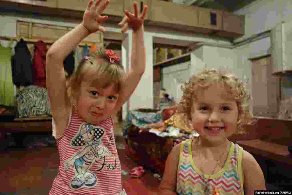 На фото: дві дівчинки граються в укритті. Дітлахи проводять більшість часу за іграми. Біганина дратує декого з сусідів по підвалу, інші ж дозволяють дітям займатися своїми справами. 