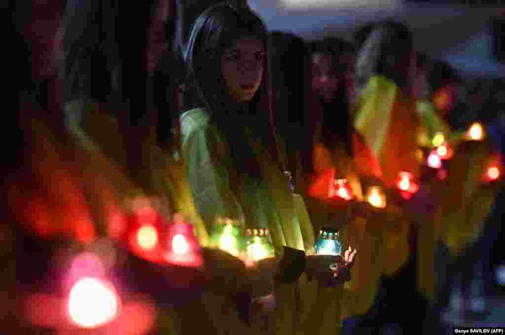 Молодь тримає свічки під час церемонії у Славутичі, де жив персонал станції. За 50 кілометрів від місця аварії. 26 квітня 2019 року  