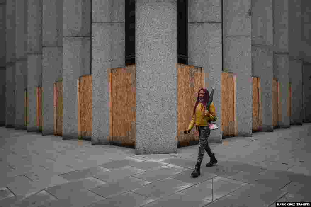 Жінка проходить повз крамницю захищену дерев'яними дошками у Вашингтоні, округ Колумбія, США