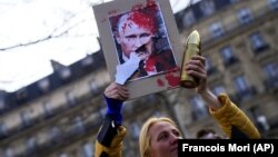 Франція. Жінка з портретом Володимира Путіна на акції підтримки України на тлі масштабного вторгнення Росії. Париж, 5 березня 2022 року