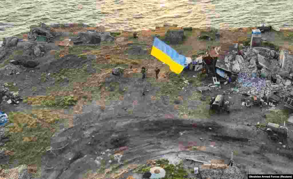 Українські бійці встановлюють національний прапор на острові Зміїний в Чорному морі (Одеська область). Фото опубліковане 7 липня 2022 року. Раніше, після тривалих інтенсивних ударів ЗСУ, російські військові, зазнавши великих втрат, залишили острів. Президент України Володимир Зеленський записав відеозвернення до українців у 500-й день повномасштабної війни з Росією на острові Зміїному, звільненому від російських військ рік тому