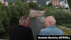 Dvojica građanina posmatraju napredak radova na jednom od novih mostova preko reke Ibar.