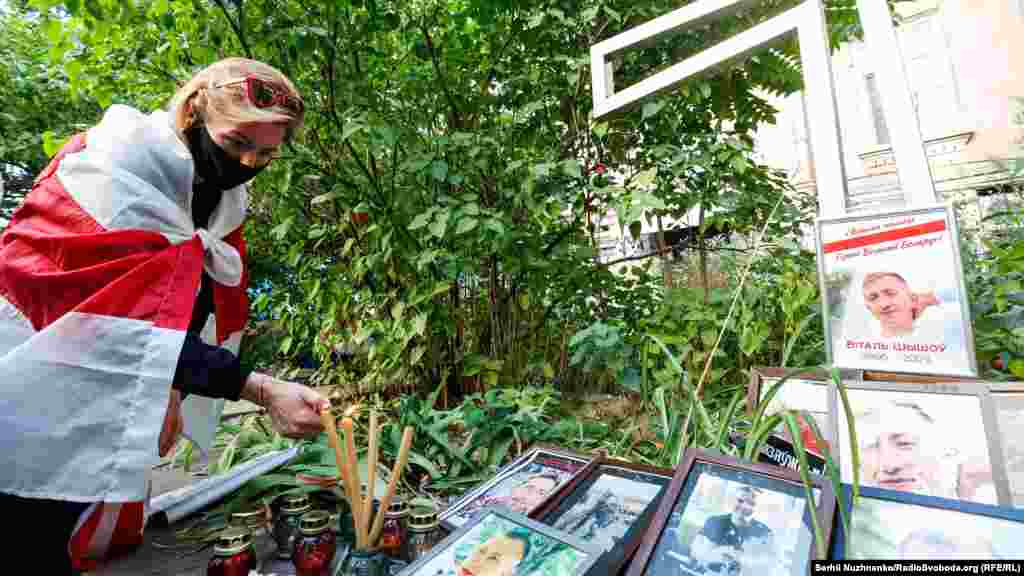 Жінка підпалює свічки біля пам'ятного хреста жертвам режиму Лукашенка, неподалік будівлі посольства Білорусі в Києві 