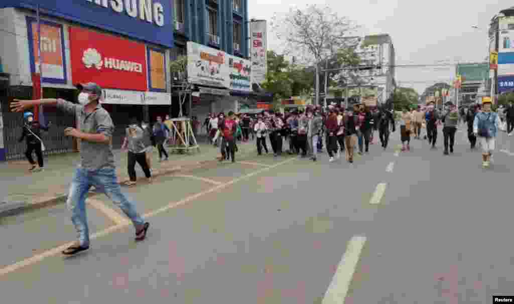 Люди евакують пораненого протестувальника під час акцій протесту у М’їчині, 8 березня