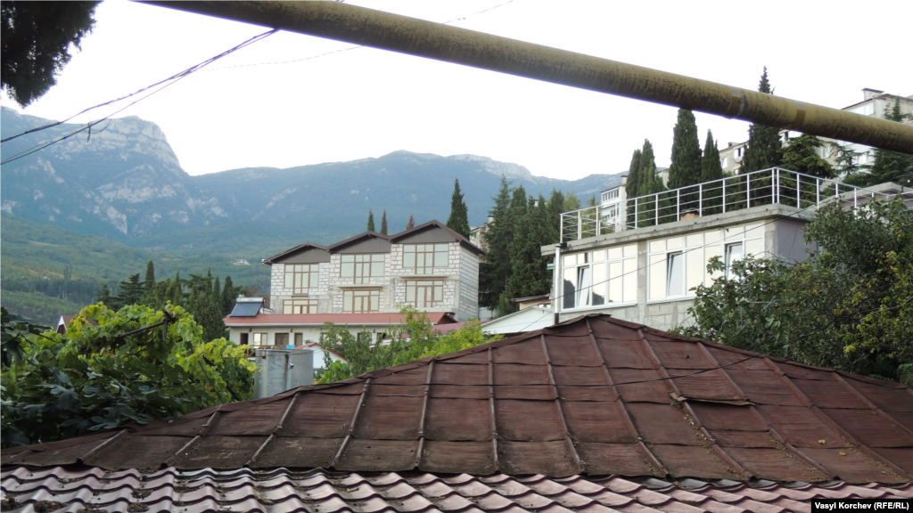 Крымские горы виднеются вдалеке над крышами – это традиционный вид из окна в Гурзуфе