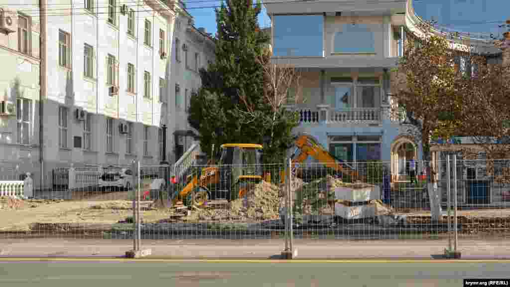 Екскаватор копає ґрунт на тротуарі біля торгового центру «Діалог»