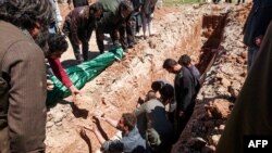 Syrians dig a grave to bury the bodies of victims of a a suspected toxic gas attack in Khan Sheikhun.