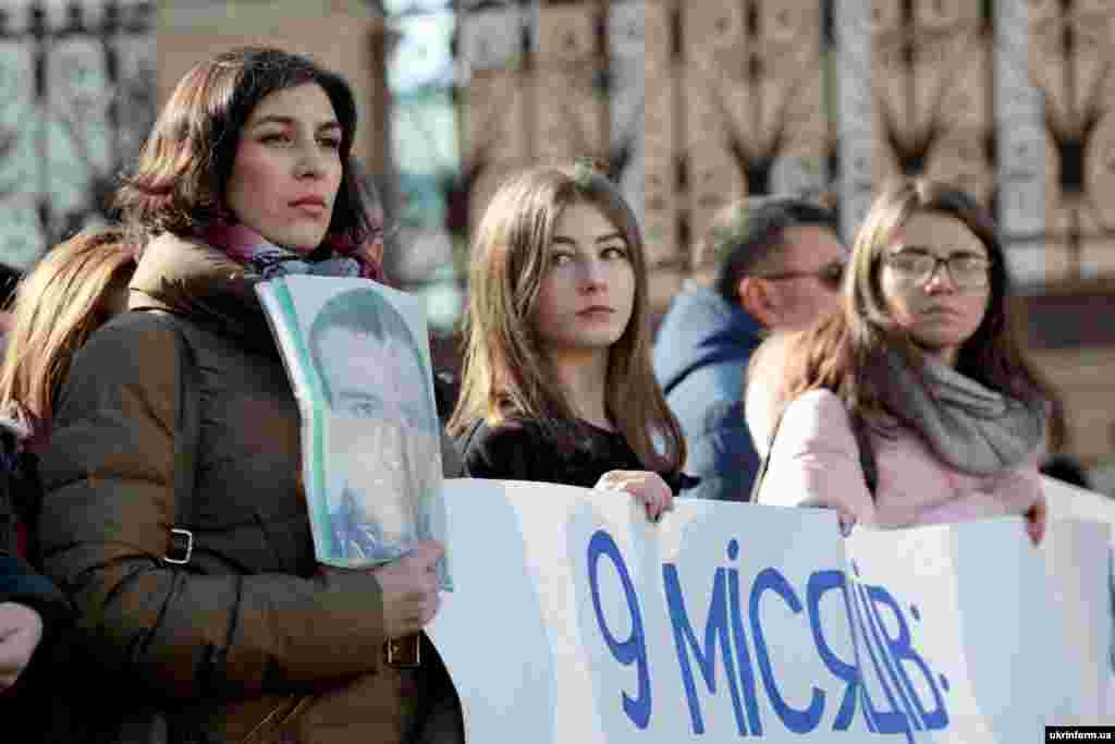  Учасники акції «Президенте, підпиши», під час якої рідні українських політв'язнів та військовополонених вимагали створити Координаційну раду з питань звільнення заручників при АП, з плакатом та портретом біля будівлі Адміністрації Президента. Київ, 13 березня 2019 року