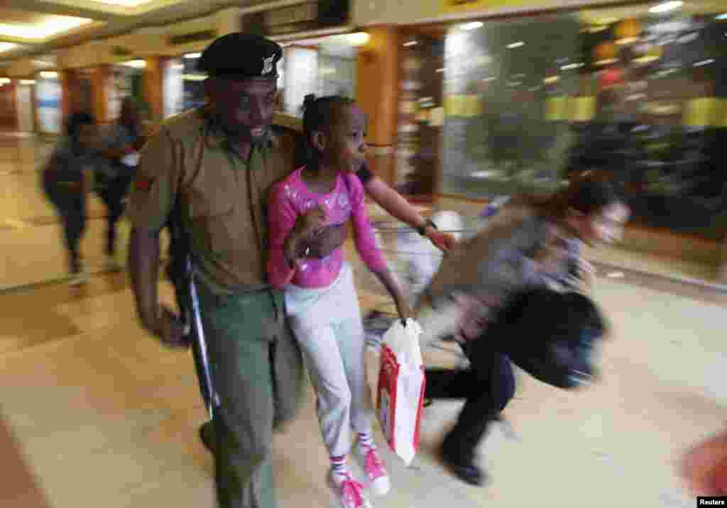 Солдат выносит ребенка из захваченного боевиками центра.