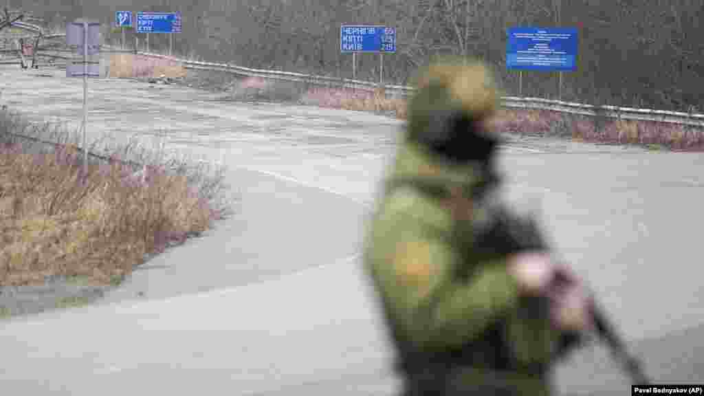 Белорусский пограничник с автоматом наблюдает за дорогой возле украинского пункта пропуска "Новые Яриловичи" в Гомельской области на границе с Украиной