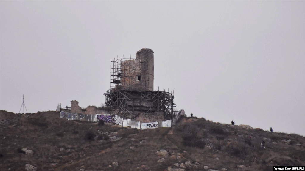 Туристы под дождем осматривают развалины крепости Чембало 