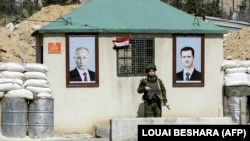 Військовий РФ між портретами президента Сирії Башара аль-Асада (праворуч) і очільника Росії Володимира Путіна на контрольно-пропускному пункті на околиці Дамаска, 1 березня 2018 року