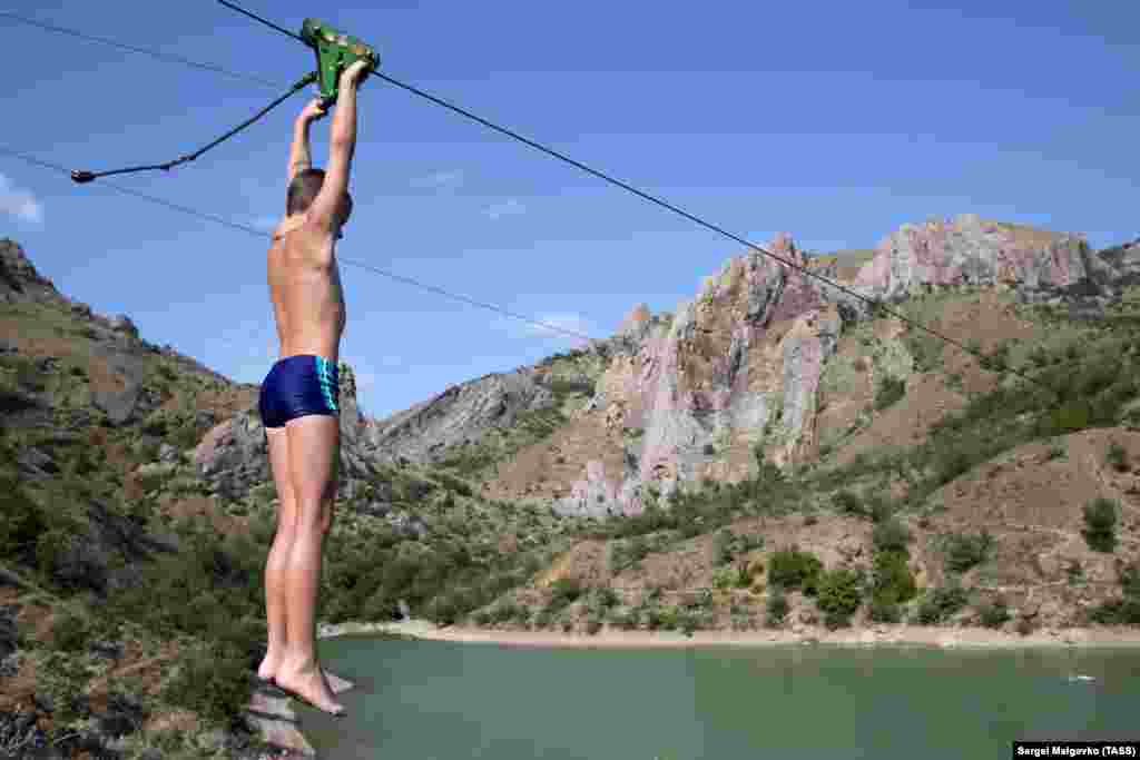 Отдыхающий пролетает на «тарзанке» над урочищем Панагия в селе Зеленогорье, которое расположено на юго-восточном побережье Крыма, между Судаком и Алуштой. Больше фото – здесь 