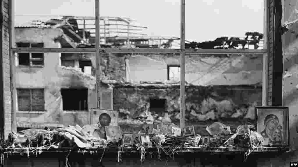 Иконы, цветы, бутылки с водой, еда и свечи на окнах спортзала. Школа №1, Беслан, Северная Осетия. 17 сентября 2004. Джеймс Хилл  