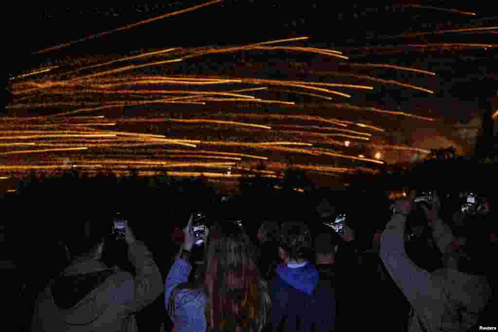 Люди фотографируют ручные ракеты, запускаемые во время празднования Пасхи по Греческому православному обряду в деревне Вронтадос на острове Хиос, Греция, 19 апреля 2025 года. REUTERS/Konstantinos Anagnostou