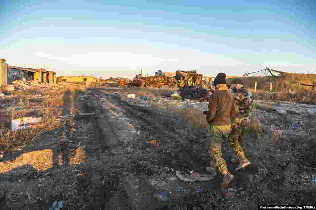 Волонтер Юрій йде біля зруйнованих складських приміщень разом із бійцем 93-ї бригади