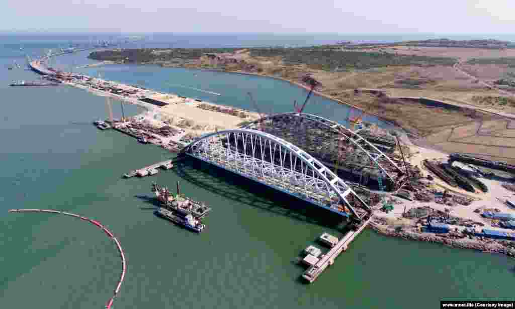 Инженер наблюдает за масштабной моделью буксируемого моста через аэродинамическую трубу. Когда настоящие арки будут перемещать на свои места, Россия объявила, что Керченский пролив будет закрыт для всех перевозок в течение 23 дней в августе и сентябре. Украина заявляет, что закрытие будет «еще одним грубым нарушением Российской Федерацией норм международного права».