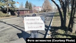 Пикетчик с видом на ворота посольства Германии. Слева можно увидеть направляющегося к нему от проходной полицейского.