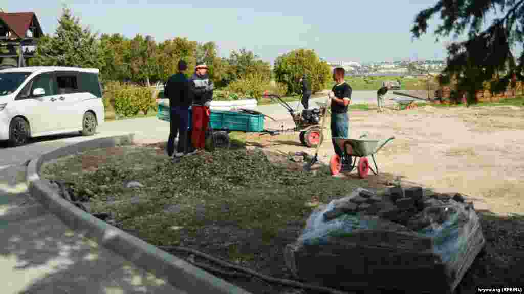 Рабочие убирают строительный мусор после завершения строительства дорожки 