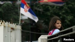 Eight-year-old Rinesa Koshi heads home past a Serbian flag as she crosses a bridge that separates the ethnically divided sections of Mitrovica, in Kosovo.