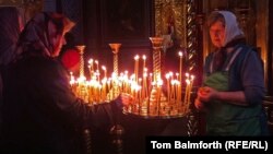 Two elderly women place prayer candles in Kyiv's St. Michael's monastery on Easter Sunday.