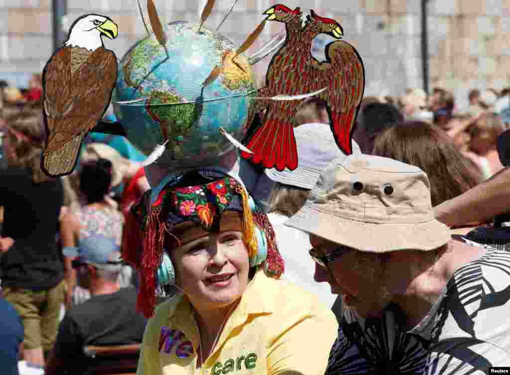 Жінка із інсталяцією на своїй голові, де пташині символи США – білоголовий орлан – та Росії – золотий двохголовий орел – своїми перами розмітили земну кулю між собою