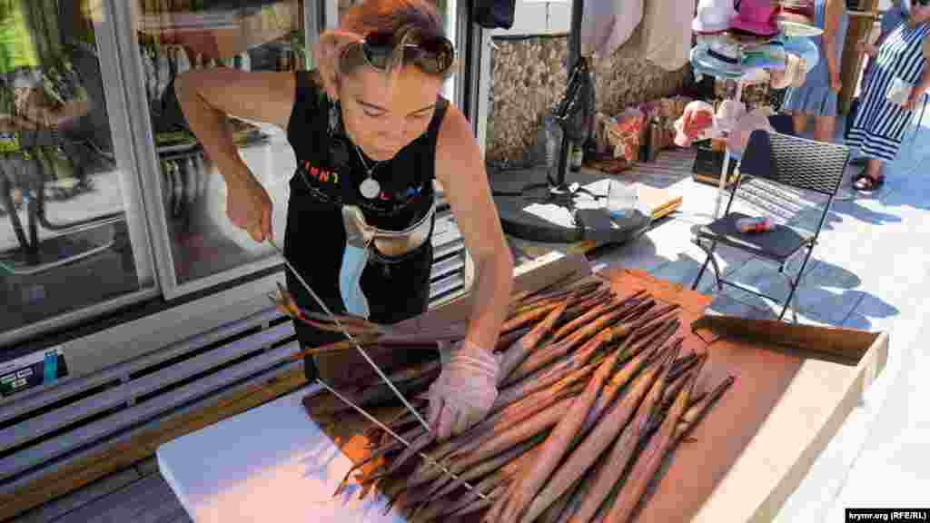 Продавец нанизывает копченую рыбу-флейту на витринные штыри. Цена одной такой флейты – 200-300 рублей (75-112 грн)