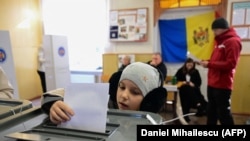 Ребенок голосует за родственника во время президентских выборов и референдума о вступлении в ЕС на избирательном участке для жителей Приднестровского региона в Варнице