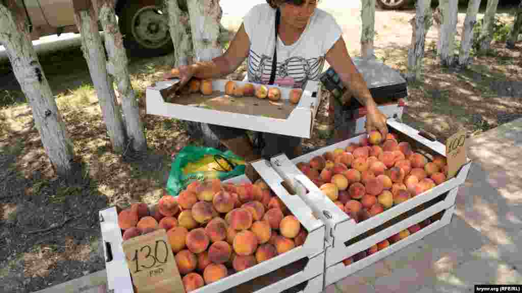 Женщина продает на обочине персики сорта «Сочный», выращенные в селе Предущельное близ Бахчисарая. По ее словам, в этом году собран неплохой урожай ранних персиков, однако значительная часть фруктов при этом пострадала от града