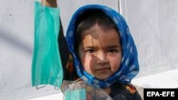 A young Afghan girl sells face masks on a road in Kabul in September.