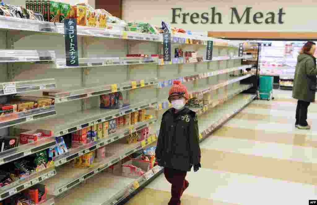 Хлопчик у масці проходить повз напівпорожні полиці супермаркету на північному заході Японії, в місті Акіта, 15 березня 2011 року. Після землетрусу з цунамі і ядерної кризи людей охопила паніка. Того дня на АЕС «Фукусіма-1» сталися ще два вибухи водню і сильна пожежа, що призвело до значних викидів радіації