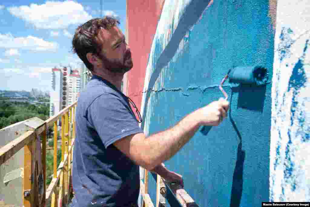 Художник під час роботи над цим 17-поверховим муралом на Троєщині на півночі Києва. Австралієць каже, що йому подобається працювати над масштабними творами поза межами елітарної атмосфери художніх галерей. «Мене захопила робота на Троєщині. Цей район географічно відокремлений від центру Києва, тому так важливо, щоб ми працювали й тут – таким чином ми можемо інтегрувати мистецтво у щоденне життя людей»  