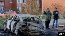 Російські правоохоронці оглядають згорілий автомобіль у дворі житлових будинків після атаки безпілотника в Московській області, 10 листопада 2024 року