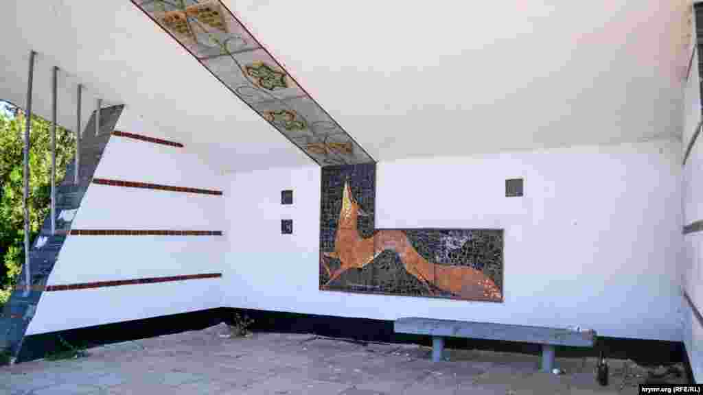 Внутри остановки – мозаичное панно с изображением лисы, виноградных листьев и гроздей. Прямо за остановкой – виноградники завода «Золотая балка»