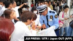 Люди на залізничній станції в японському місті Осака 18 червня 2018 року