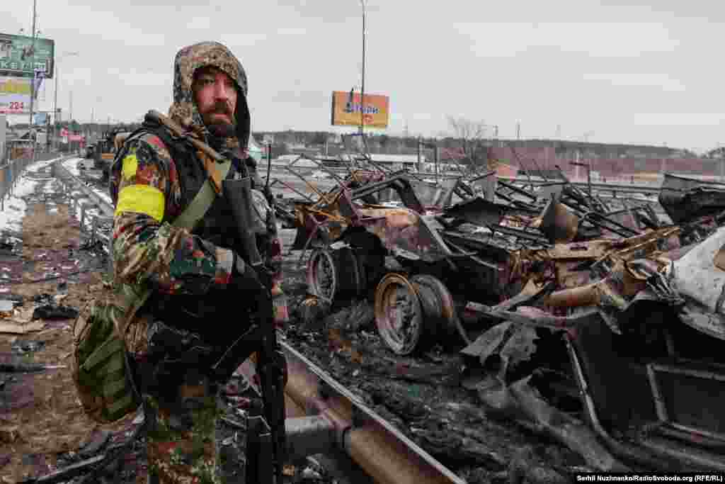 1 березеня 2022 року. Військовий ЗСУ дивиться на рух на іншій стороні Гостомельського мосту на Київщині. Стоячи біля знищеної колони російського ОМОНу, яка проривалася до столиці, він звернувся до матерів солдатів РФ: «Подивіться, якщо приїдуть ваші чоловіки до нас, матері, подивіться на них. Навіщо ви їх сюди пускаєте? Ми їх покладемо, усі колони, але Україну ми не здамо»