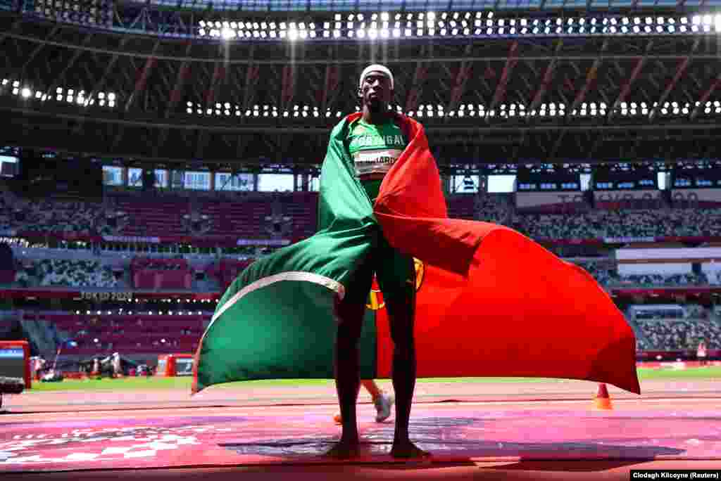 Португалец Педро Пабло Пичардо празднует «золотую» победу в финале по тройному прыжку среди мужчин, завернувшись во флаг Португалии