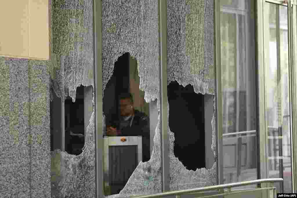 Чоловік сидить за розбитим вікном у федеральній будівлі Рональда В. Деллумса в Окленді, Каліфорнія. 26 липня 2020 року