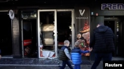 People in Podgorica walk past a vandalized Turkish restaurant.