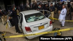 Investigators examine the scene where gunmen opened fire on two Chinese workers in Karachi on July 28.