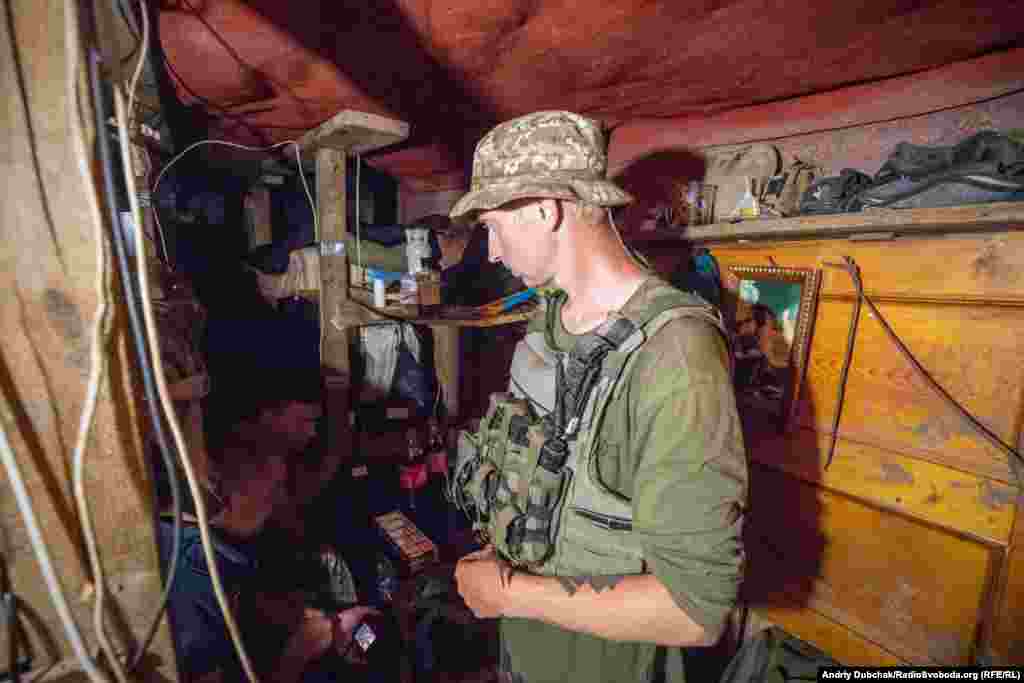 Позиції – це вкопані в землі спостережні та вогневі точки у полі, які з'єднані між собою лініями окопів. Вони оточують майже все село. Живуть військові, у глибоких бліндажах. Місця небагато, але це досить надійний захист від артобстрілів, які тут відбуваються часто. На фото – матрос із позивним «Нік» в одному зі «спальних» бліндажів морпіхів