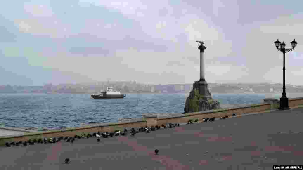 Голуби прячутся от ветра за парапетом у Памятника затопленным кораблям. На заднем плане – паром, перевозящий автомобили и пассажиров на линии Северная сторона – Артиллерийская бухта