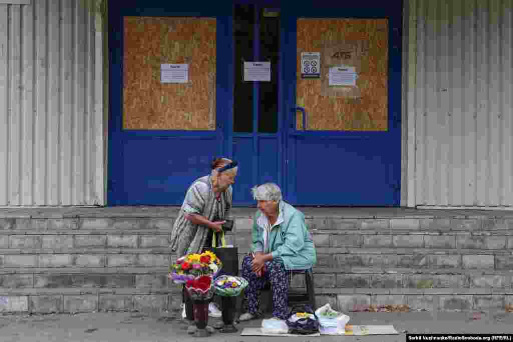 Жінки біля зачиненого супермаркету продають квіти й городину. У Покровську зачинені всі великі супермаркети і ТЦ, працюють лише невеличкі продуктові магазини