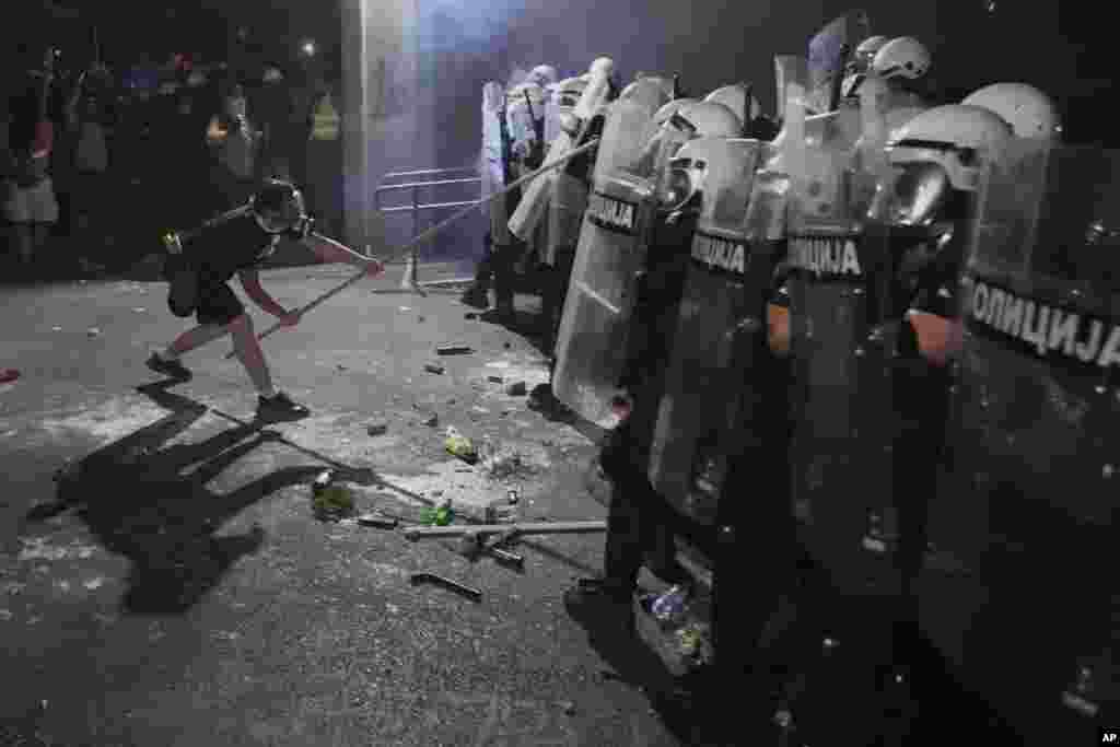Демонстрант со гас-маска ги удира штитовите на полицајците во кордонот во Нови Сад. 5 септември 2025 година